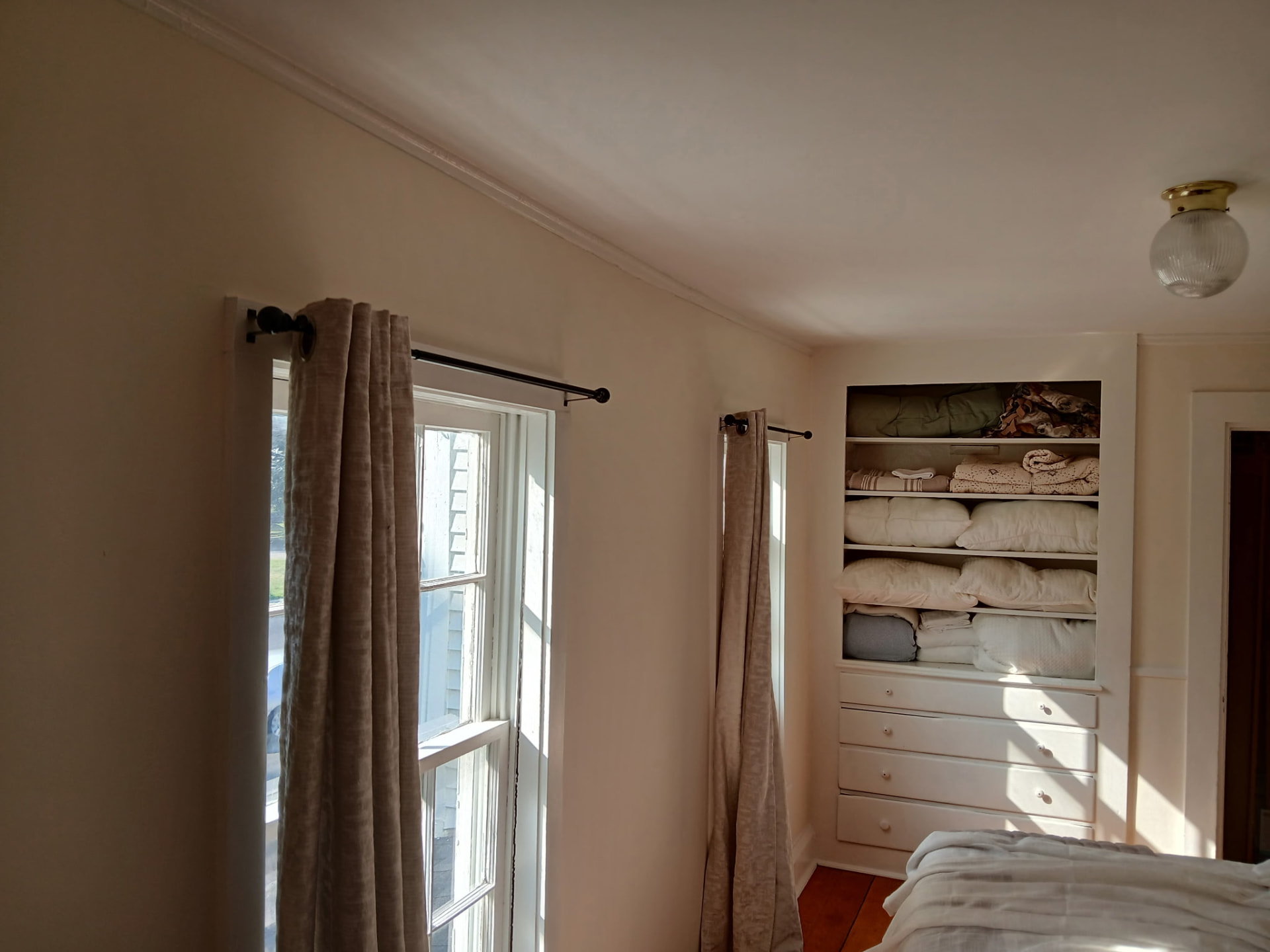 Sunlit bedroom with soft cream walls and built-in white shelving