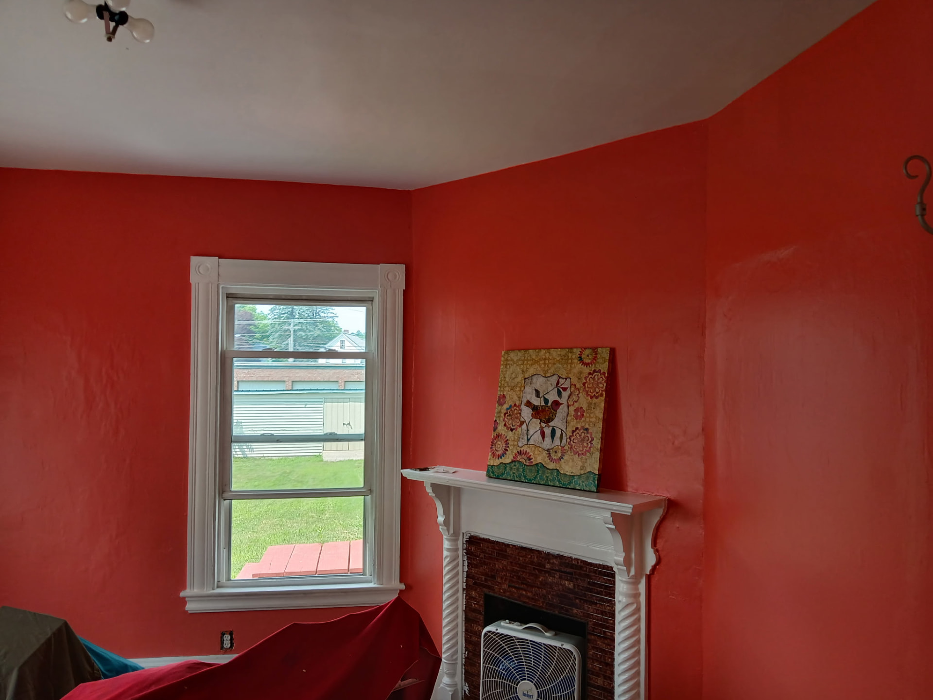Bold red-orange accent room with white fireplace mantel and trim